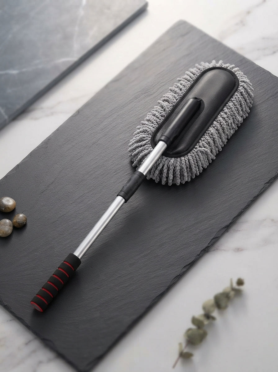 A premium extendable microfiber car duster resting on a charcoal slate surface, highlighting the soft texture of the brush.